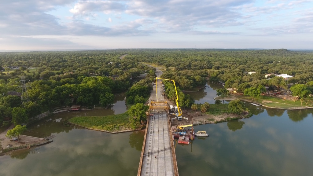 Bridge construction over a river in Kingsland, Texas with a pump truck and concrete trucks