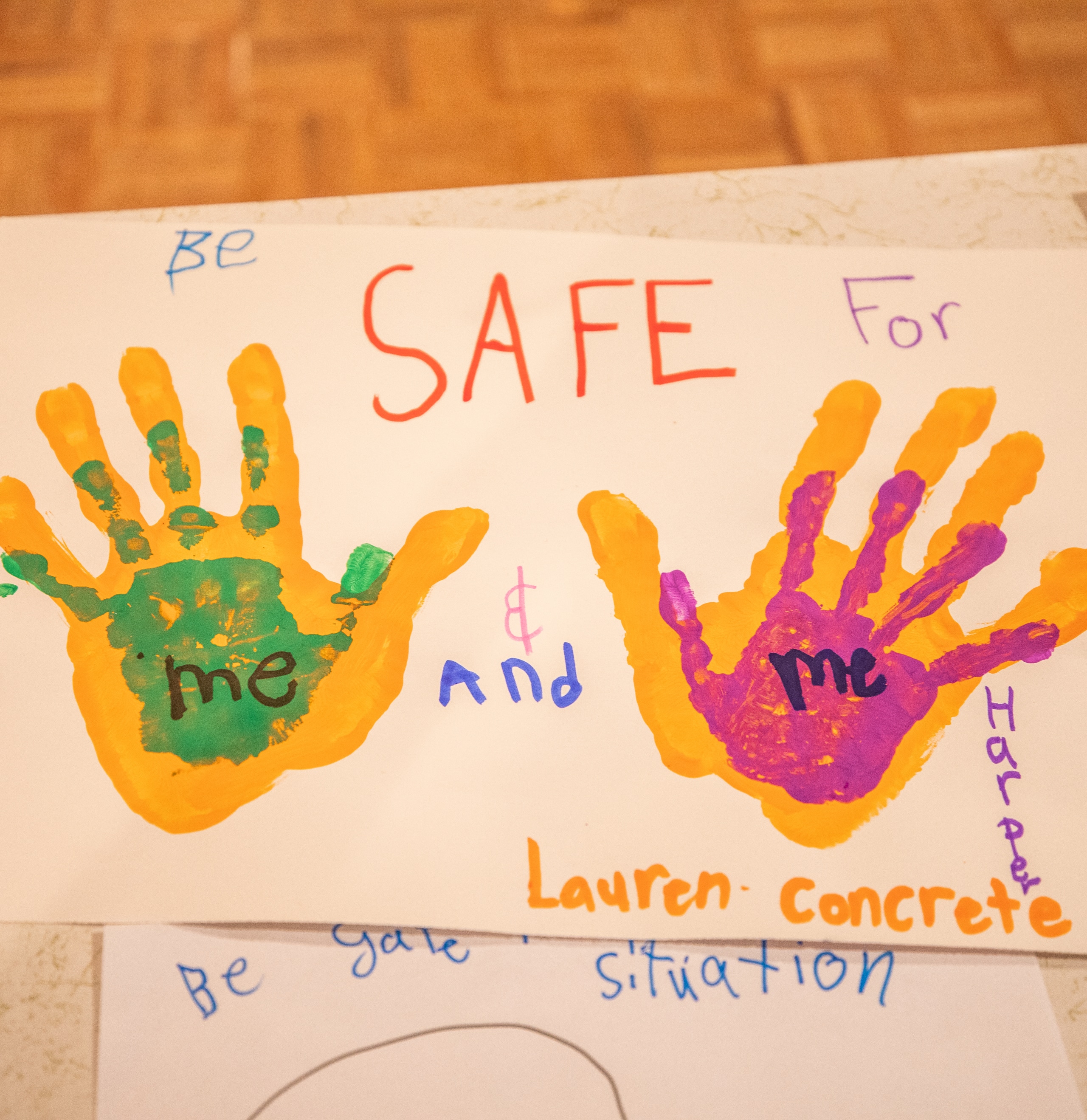 A picture painted by two children stating "Be Safe for Me and Me" with their hand prints in paint